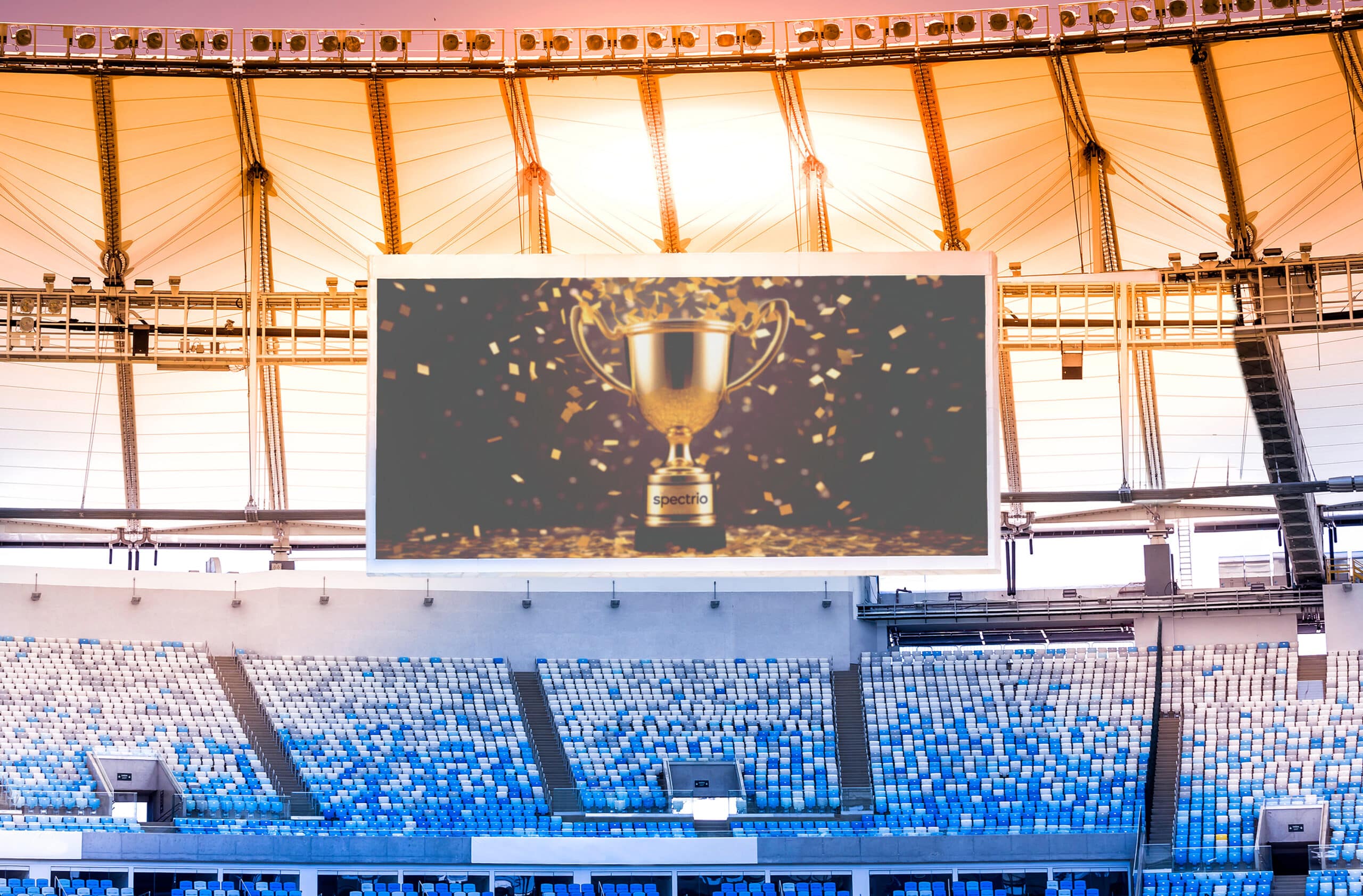 Large video screen hanging in a stadium with an image of a trophy with confetti and the inscription of Spectrio on the base