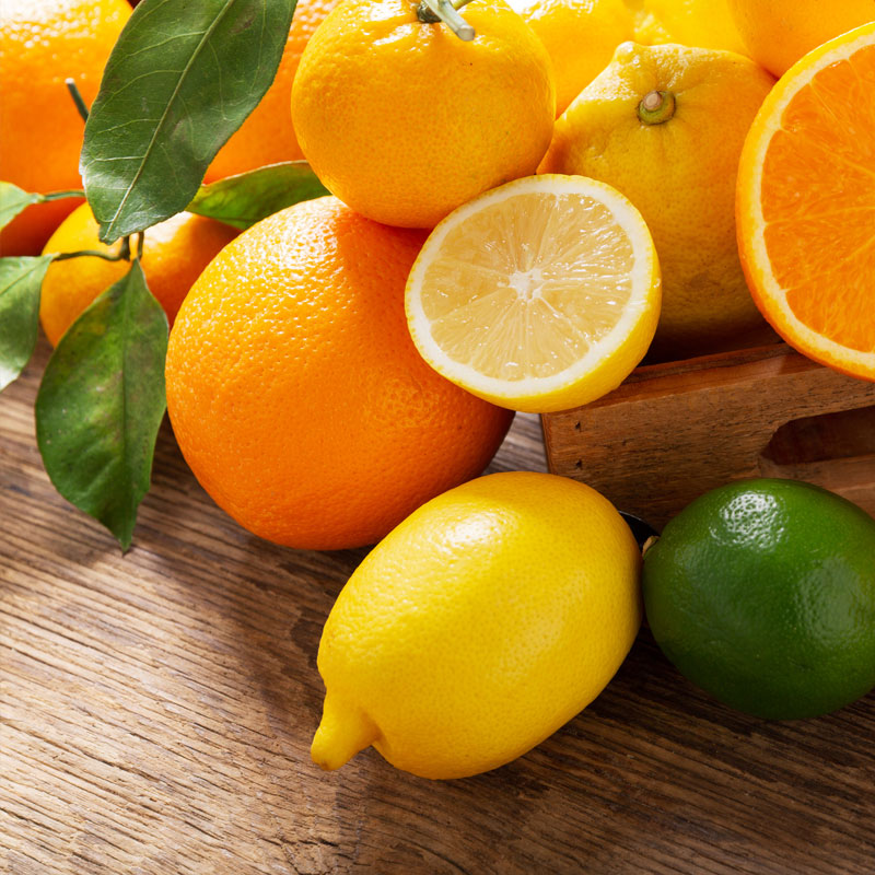 Fresh citrus fruits, including oranges, lemons, and limes, on a wooden table in the USA.