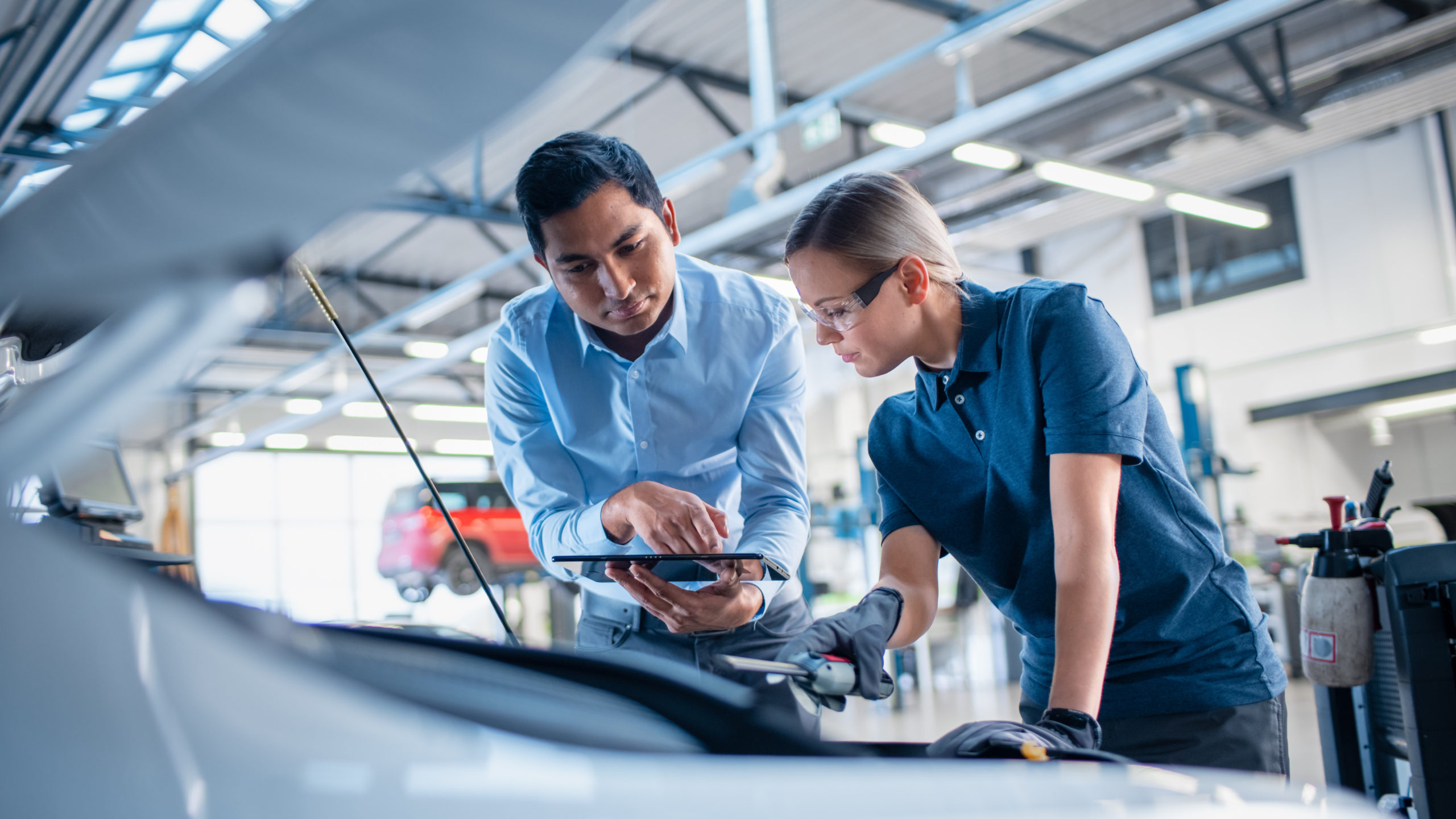 Instructor at a car with a table giving a task for a student, or customer