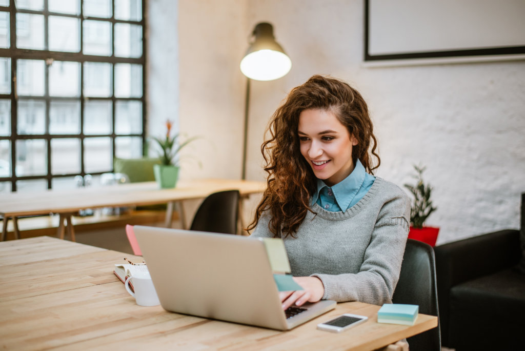 happy woman working on laptop in living room